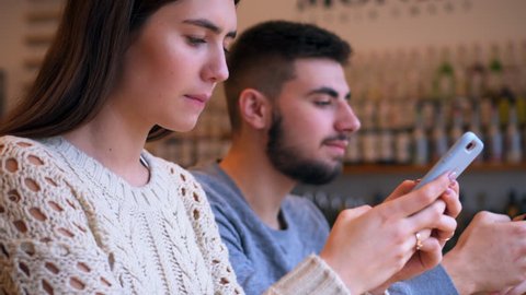 Girl and boy texting on phones while sitting at cafe
