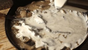 ?ream is poured into the mushroom sauce closeup. Video
