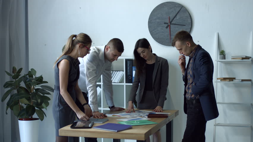 Successful business team analyzing charts and graphs to gain better future results while standing at table during meeting. Business people discussing current situation on market and planning strategy Royalty-Free Stock Footage #1007031340