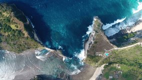 Aerial view by drone 4k camera. Rocks in a blue sea lagoon with breaking waves. Rock in the ocean at Atuh beach on Nusa Penida island, Indonesia. 