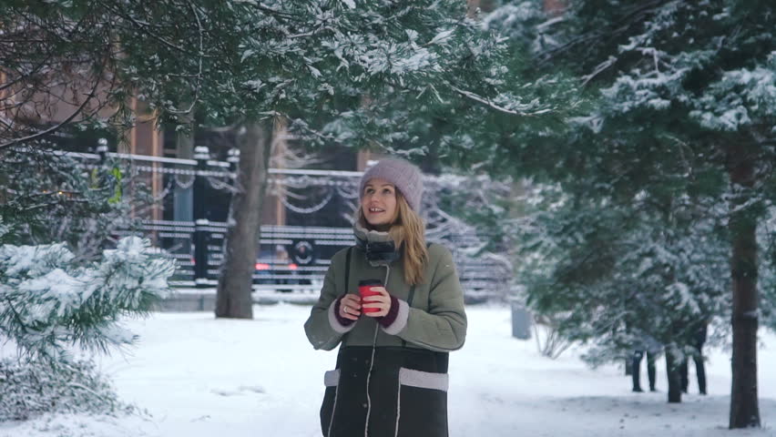Young happy woman shaking a tree branch with snow