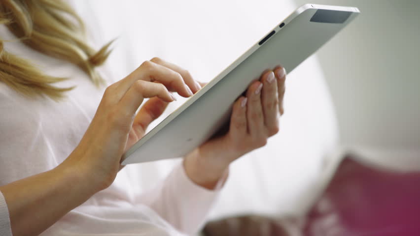 Young blonde woman seraching with tablet on couch