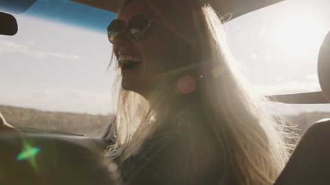 Laughing woman in car holding cell phone and pointing in slow motion / Hanksville, Utah, United States