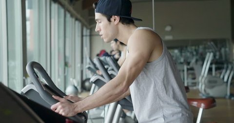 A guy in the gym to stay fit and have defined muscles or lose weight runs on the treadmill with a lot of energy. Concept of: sport, gym, muscles and fitness