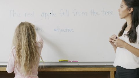 Teacher watching girl at whiteboard in English class / Provo, Utah, United States