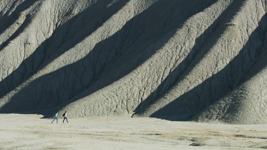 Distant girls hiking near remote rock formations / Caineville, Utah, United States