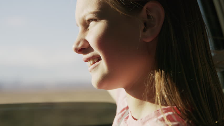 Close up of girl in car with arm outstretched enjoying wind / Hanksville, Utah, United States