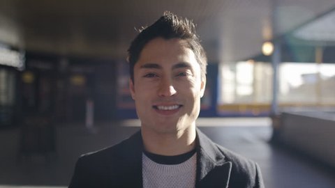 Portrait of handsome asian man looking to camera and smiling, in slow motion