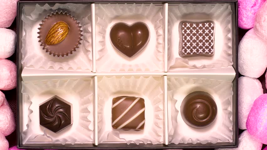 PIECES of CHOCOLATE in a GIFT BOX.  PINK HEART SHAPE background.