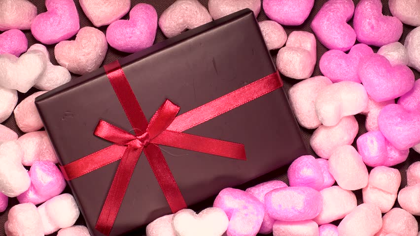 PIECES of CHOCOLATE in a GIFT BOX.  PINK HEART SHAPE background.