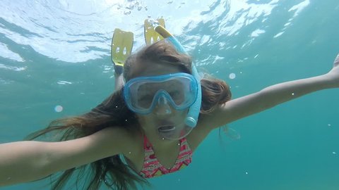 Little caucasian girl with flippers, mask and snorkel swimming in the sea, gopro underwater footage