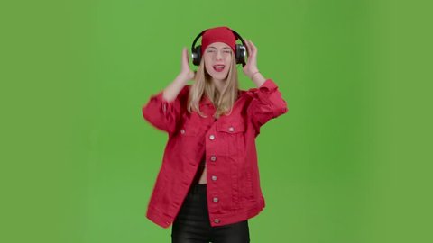 Girl listens to music on headphones with energetic songs. Green screen