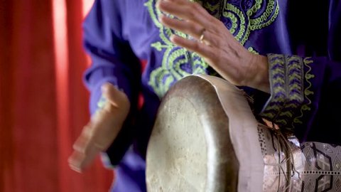 Closeup of a female Arabic percussionist playing the rhythm beladi on a decorated clay doumbek with fish skin head.