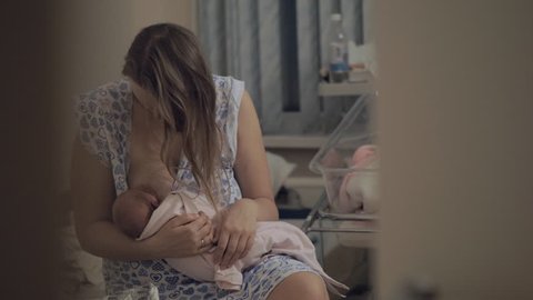 Mother breastfeeding newborn baby in maternity hospital at night