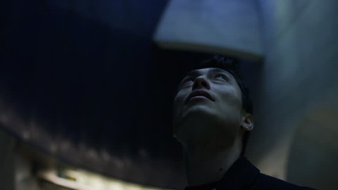 Attractive young man looks up to a faint light above him, in slow motion