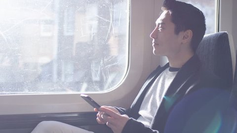 Confident man on a train journey using his phone, in slow motion