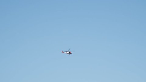 Low-angle side view shot of an helicopter in motion flying down against clear blue sky