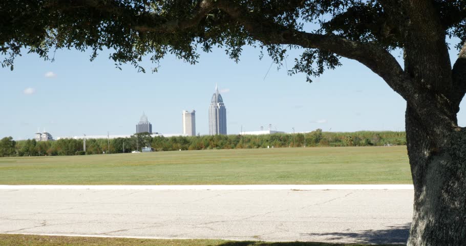Mobile Alabama City Zooming shot of three modern buildings in a green area with vegetation against clear sky in a sunny day in a summer