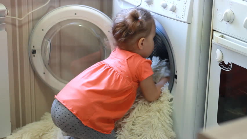 Funny cute little girl puts dirty things in the washing machine. Baby and laundry. Royalty-Free Stock Footage #1007096332