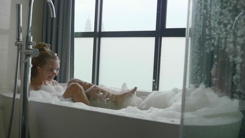 Beautiful woman relaxing in bubble bath lying in bathtub. Beauty care, leisure activity and healthcare concept.