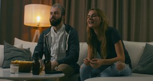 Young adult Caucasian couple watching sports on TV, cheering for the favorite team. 4K UHD