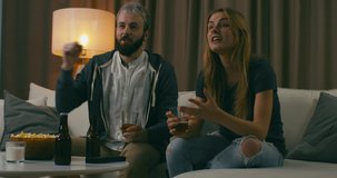 Young adult Caucasian couple watching sports on TV, cheering for the favorite team. 4K UHD