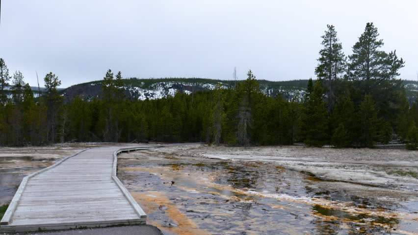 Tourist at walkway  overlooking hot springs in the West Thumb Geyser Basin at Yellowstone National Park in Wyoming, USA