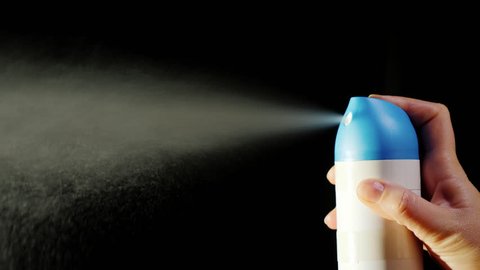 A close-up of an aerosol can. Spray spray on a black background