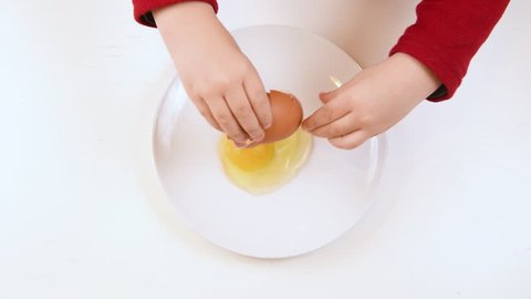 Baby hands doing experience in cracking egg, high angle view concept of successful acquiring ability
