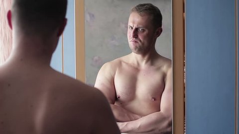 Funny narcissist guy straining his muscles in front of the mirror