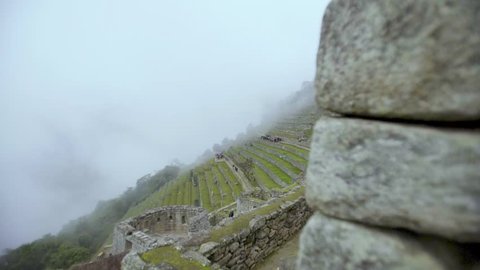 Machu Picchu Landscape reveal. Slow track past ancient stone wall to reveal misty Machu Picchu.