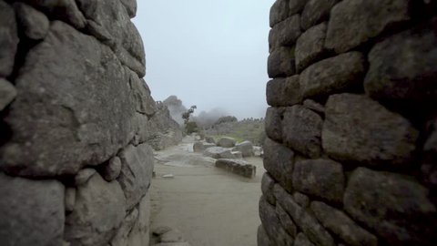 Machu Picchu. Slow track through stone doorway to reveal llamas