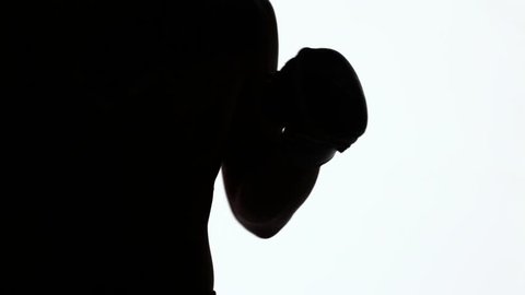 A fighter without rules trains punches and elbows. Silhouette of a sporting young man during melee in martial arts classes. Sports training. Black object isolated on white background.