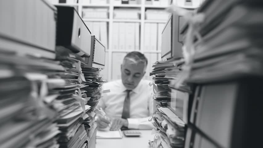 Tired overworked businessman working in the office, his desk is filled with paperwork: work overload and stress concept, dolly shot | Shutterstock HD Video #1007116546