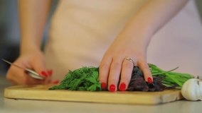 Glamorous girl's hands cutting the greens: parsley, dill, basil, vegan cooking close up 