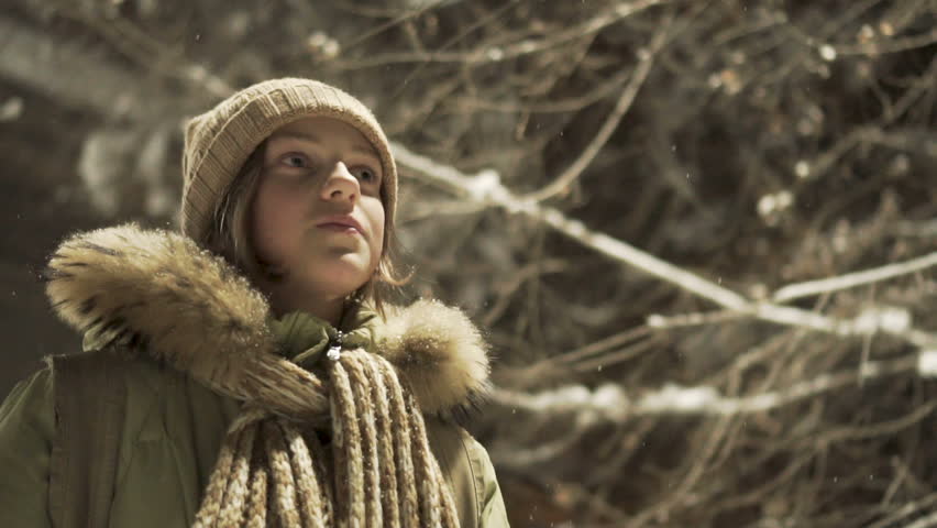 Close-up portrait of a young girl teenager restraining smile. Winter mood, snowing. Slowmotion. Real people series