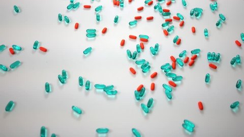 Spinning blue and orange pills over white studio background - Above Angle view