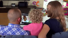toddler girl with mom and dad watch family movie on tablet computer. 4K