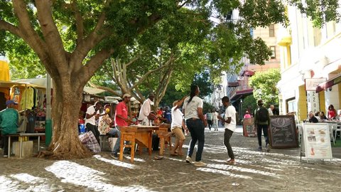 CAPE TOWN, SOUTH AFRICA, CIRCA FEB 2018, Three young African men dancing to street music in Greenmarket square one with selfie stick, under tree. 