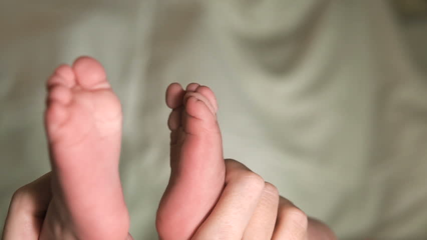 The baby moves his toes with his fingers. Mom holds the small feet of the newborn. Mother caresses the child's legs. Slow motion, rapid. | Shutterstock HD Video #1007140606