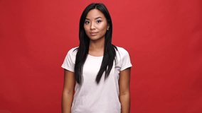 Happy asian woman in t-shirt rejoice over red background