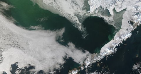 Very high-altitude overflight aerial of a frozen Bering Sea and west coast of Alaska. Clip loops and is reversible. Elements of this image furnished by NASA