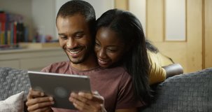 4K Young attractive couple streaming media on digital tablet & chatting. Slow motion.