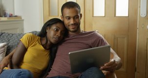 4K Attractive couple relaxing at home, streaming a movie on computer tablet
