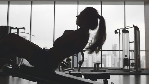 Sportswoman doing situps in gym. Muscular female athlete doing abs workout in super slow motion. Silhouette of slim athletic girl. Active and healthy lifestile concept.