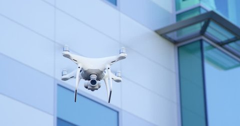 Modern drone quadcopter flying with business building in background 