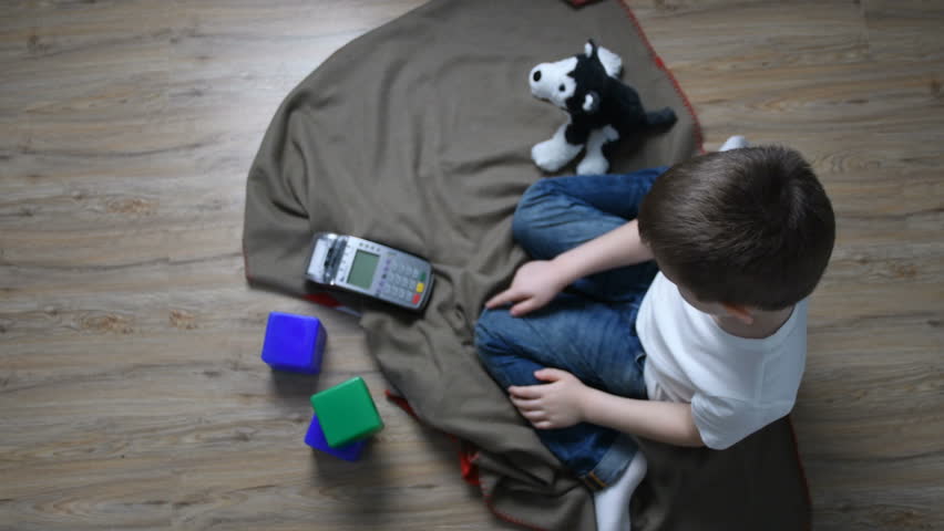Young boy sitting on the floor pressing pos terminal buttons. Modern technologies for kids. Pos machine practice. Kids education. Play and learn.