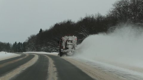 Snow-removing machine removes snow from the road. back view Slow motion