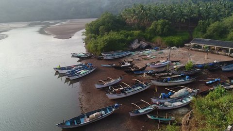 A small parking lot for a lot of fishing boats. Several coloured wooden boats and dinghys stand on the shore in anglers village in Goa, India. Aerial view.
