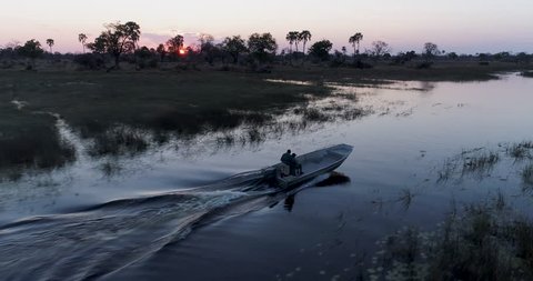 Close-up aerial view of a tourist boat at sunset driving on a lagoon in the Okavango Delta, Bostwana
